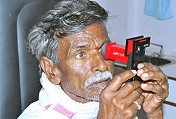 Man in India self-administering an eye exam using a NETRA wireless device